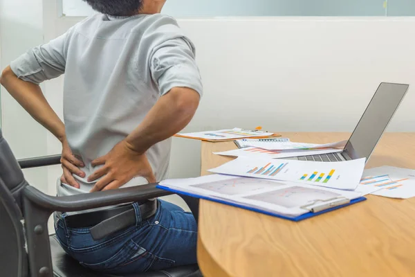Erschöpfter Geschäftsmann mit Rückenschmerzen sitzt vor Laptop — Stockfoto