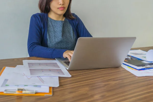 Mujer joven se concentra en trabajar con el ordenador portátil junto a los documentos — Foto de Stock