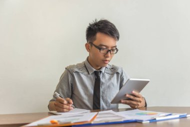 Genç Asyalı adam tablet ve yazı kullanıyor.