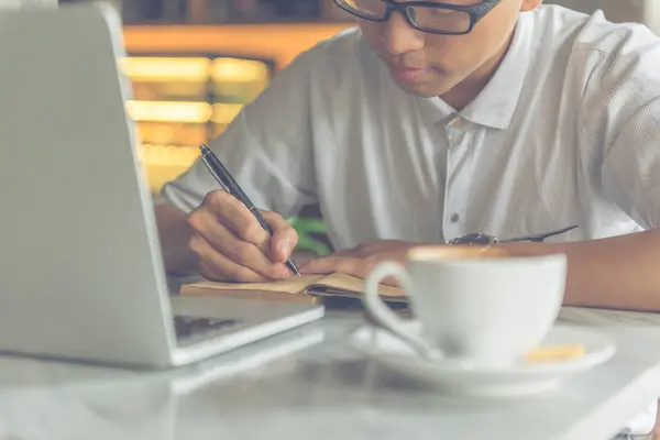 Asiatisk man skriver anteckningar på caféet — Stockfoto