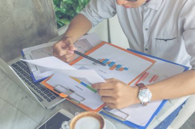 Ofisteki adam elinde kalem ve mali raporları tutuyor.