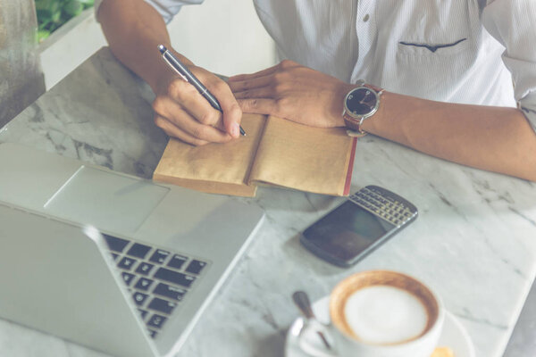 Close up photo of man writing into notes