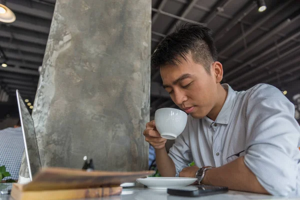 Joven millennial disfrutando del café caliente mientras trabaja en el ordenador portátil — Foto de Stock
