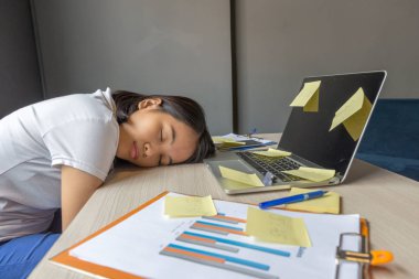 Bitkin bir kadın, düzensiz bir masada uyuyor.