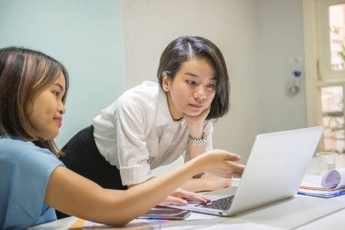 Ofiste dizüstü bilgisayarda çalışan Asyalı işadamları