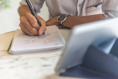 Tablet üzerindeki bilgileri izleyen ve notlar yazan adam