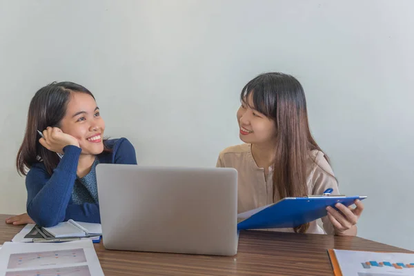 Dos señora de la oficina sentado con el ordenador portátil y tener una conversación feliz — Foto de Stock