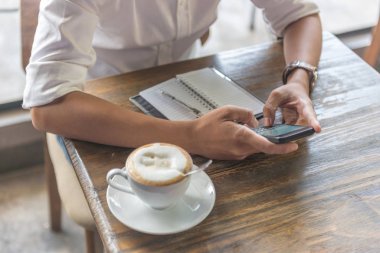 Genç adam mesaj atmak için telefonu kullanıyor.