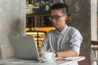Dizüstü bilgisayarda çalışan Asyalı bir adam.