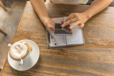 Kahve dükkanında akıllı telefon kullanan bir kadın.