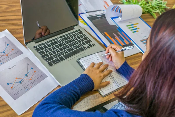 Ázsiai pénzügyi könyvelő írás notebook mellett laptop és dokumentumok — Stock Fotó