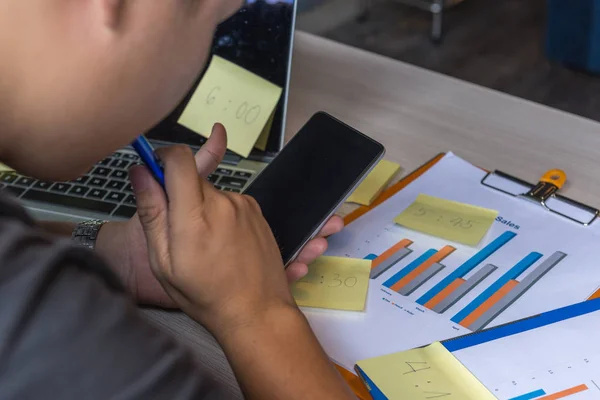 Close up of man working on sales report, using cell phone — стоковое фото