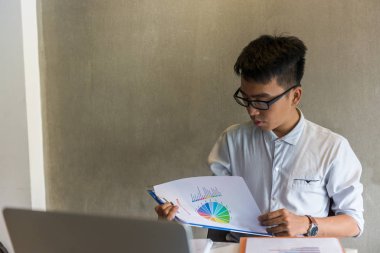 Belge üzerindeki verileri kontrol eden Asyalı bir ofis çalışanı