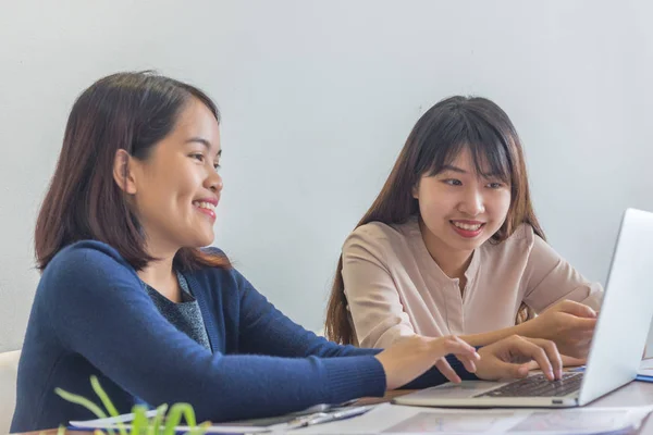 Dos mujeres de negocios sonrientes usando el ordenador portátil mientras tienen una reunión de negocios — Foto de Stock