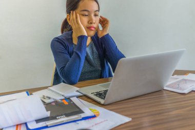 Hüsrana uğramış ofis hanımı dizüstü bilgisayar ve kağıt işlerinin önünde oturuyor.