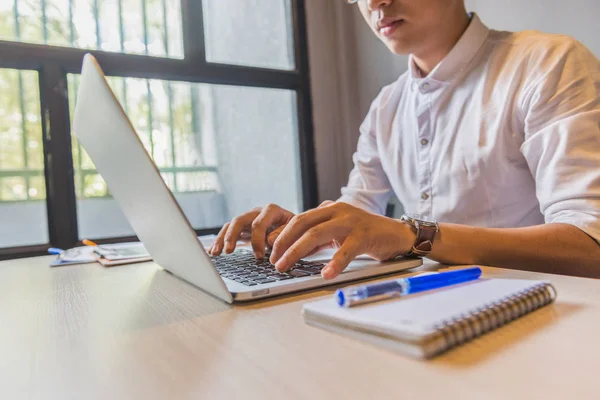 Asiatisk man i vit skjorta skriva laptop bredvid fönstret — Stockfoto