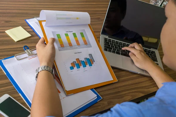 Empresario leyendo informe financiero y escribiendo en el ordenador portátil — Foto de Stock