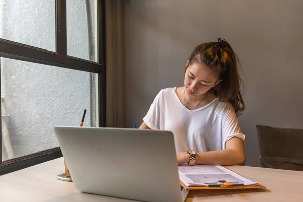 Mujer joven que trabaja en documentos y portátil — Foto de Stock