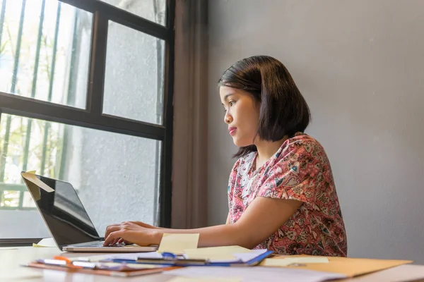 Mujer con ropa casual trabajando en casa junto a la ventana — Foto de Stock