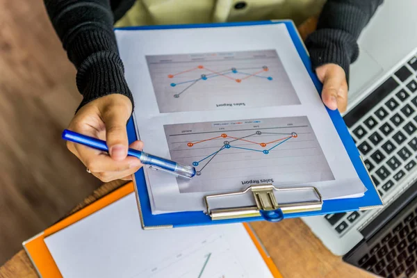 Primer plano de la mujer que sostiene el punto de la pluma en la estadística del diagrama de ventas — Foto de Stock