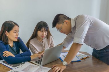 Bir grup iş adamı dizüstü bilgisayardaki mali numarayı tartışıyor.
