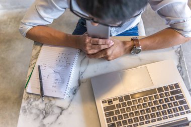 Bilgisayarda çalışan Asyalı ofis sahibinin yüksek açılı görüntüsü