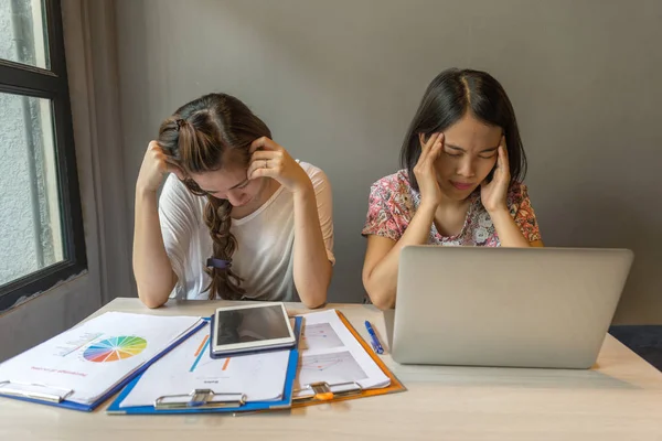 Duas jovens mulheres de escritório se sentem cansadas e estressadas com o documento financeiro — Fotografia de Stock