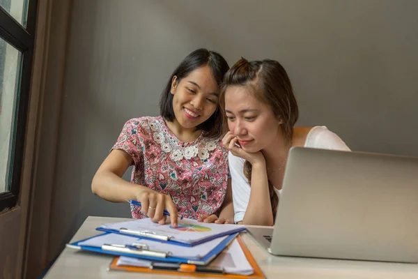 Dos mujeres felices jóvenes que trabajan con el ordenador portátil y el documento de negocios — Foto de Stock