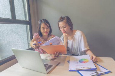 Ofiste mali belge raporlarını okuyan iki ofis kadını.