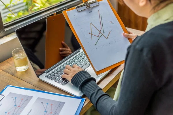 Mujer freelancer trabajando en laptop con documento estadístico de ventas — Foto de Stock