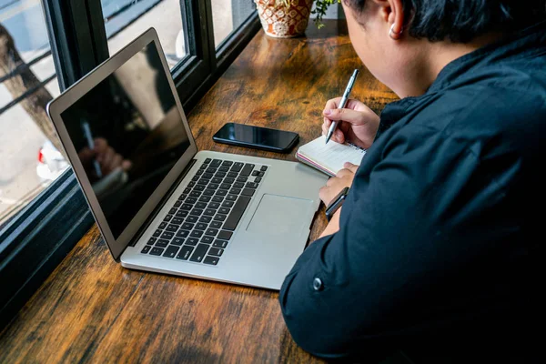 Freelancer asiático escribiendo cuaderno en mesa de madera rústica — Foto de Stock