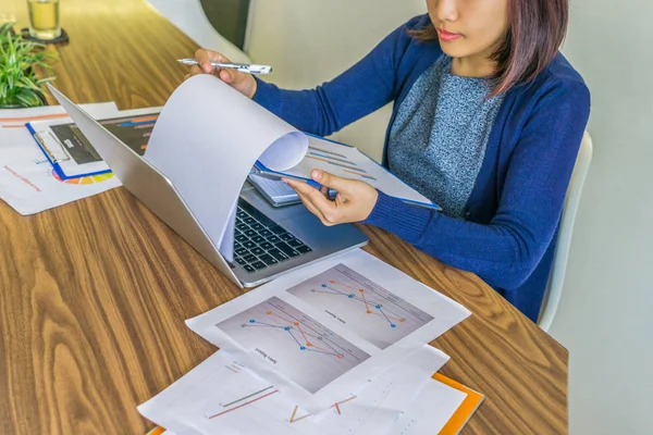 Asian office lady working on laptop and financial chart document