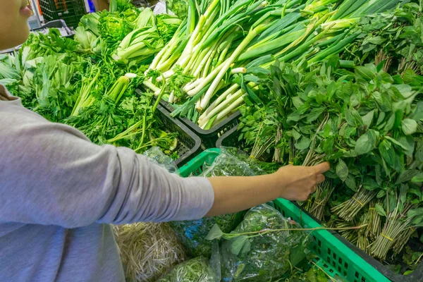 Женщина покупает зеленую петрушку в овощной ларьке на рынке — стоковое фото