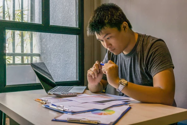 Joven freelancer asiático trabajando en laptop y documentos — Foto de Stock