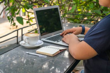 Dışarıdaki sehpada dizüstü bilgisayarda çalışan serbest çalışan biri.