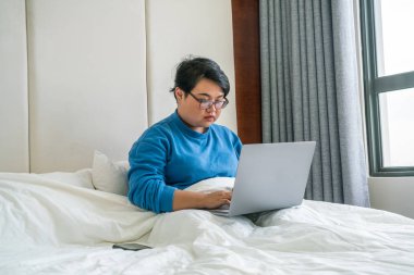 Otel odasında dizüstü bilgisayar kullanan Asyalı kadın.