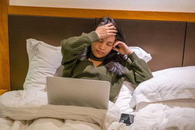 Genç bayan yatakta baş ağrısı hissediyor.