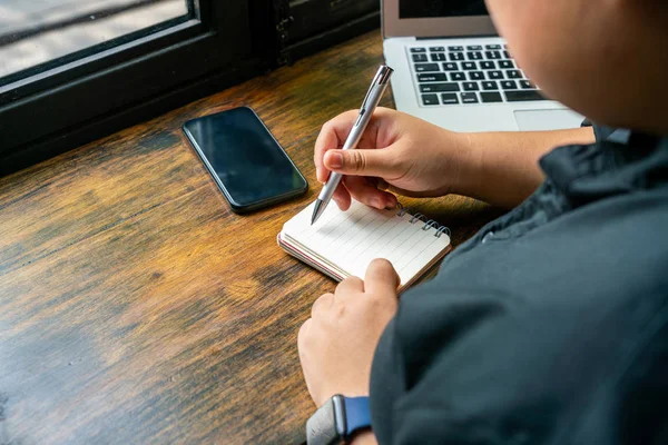 Freelancer escribiendo cuaderno diario al lado de la computadora y el teléfono celular — Foto de Stock