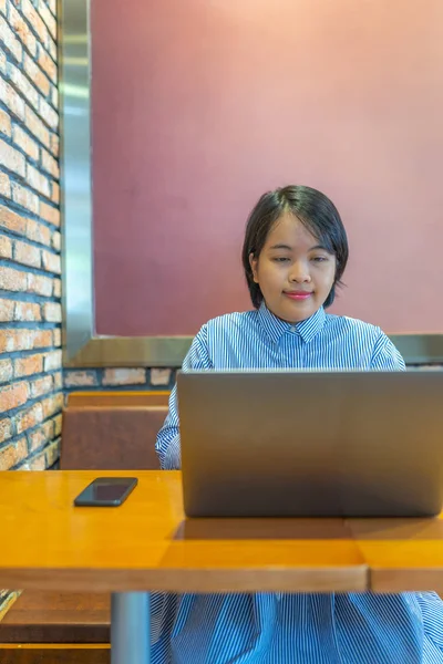 Retrato de una joven feliz usando un portátil en un lugar de trabajo bien decorado — Foto de Stock