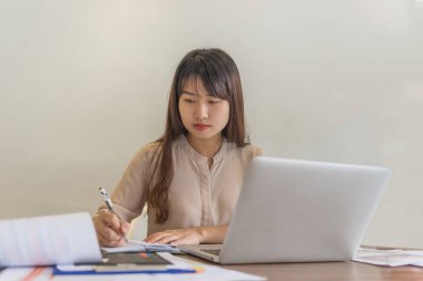 Asyalı çalışan ofis odasında notlar yazıyor.