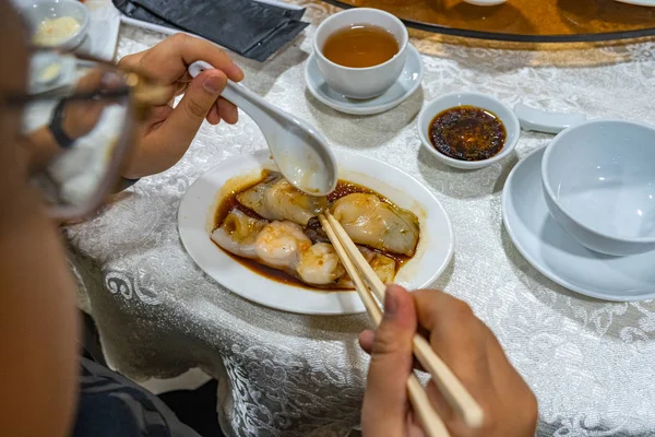 Mensch mit Essstäbchen beim Essen chinesischer gedämpfter Garnelenrollen — Stockfoto