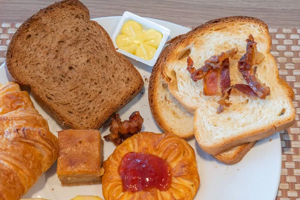 Närbild av brunt bröd, croissant, smör, jordgubbssylt — Stockfoto