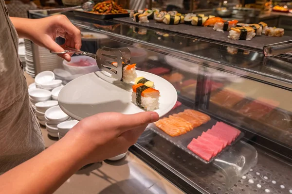 Human choosing fresh and delicious nigiri in sushi buffet counter — Stock Photo, Image