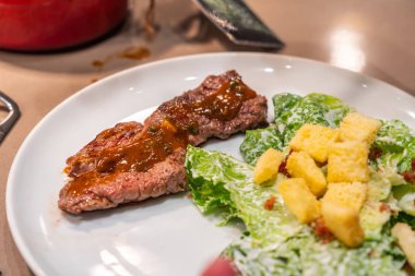 Akşam yemeğinde biftek ve salata var.