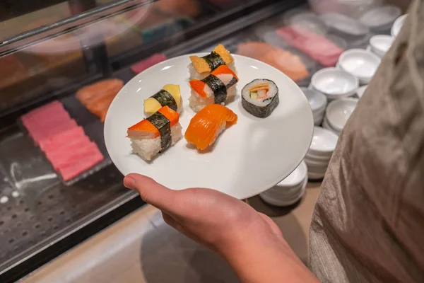 Close up photo of human holding dish of assorted sushi — ストック写真