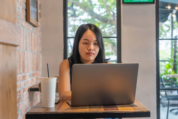 Черные волосы женщина работает на ноутбуке за журнальным столиком — стоковое фото