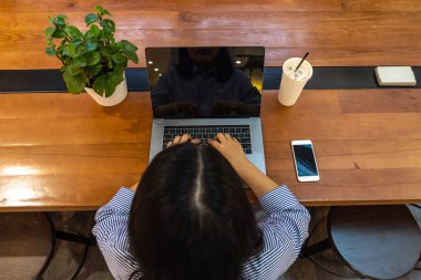 Tahta masa üzerinde çalışırken dizüstü bilgisayar kullanan serbest çalışan