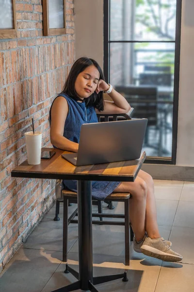 Mujer joven sentada con laptop y cerrando los ojos — Foto de Stock