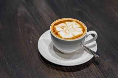Latte Art Cappuccino 'nun tahta masadaki dikey fotoğrafı.