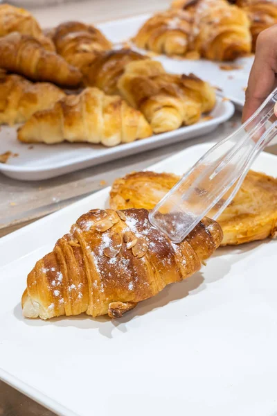 Il primo piano di croissant è stato raccolto da morsetto a pasticceria — Foto Stock